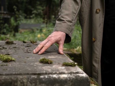 Un hombre posa su mano sobre una tumba