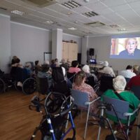 Urriaren 1a, Adinekoen Eguna Un grupo grande de personas mayores sentadas en una sala frente a una pantalla en la que se proyecta la película "Elsa y Fred"