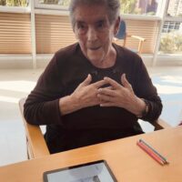 Emozioak lantzen Osasun Mentalaren Munduko Egunean Emakume adineko batek emozioz betetako hainbat aurpegitako irudiak dituen tableta bat ikusi du