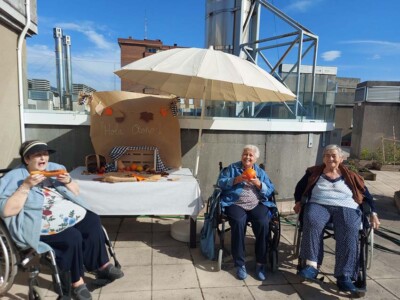 Kaixo, udazkena! Tres personas mayores, en una terraza decorada con motivos del otoño