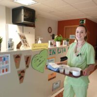 Zaintzaileen Nazioarteko Eguna Una auxiliar de enfermería posa con una bandeja en