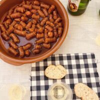 Aurten ere, San Tomas Una cazuela con txistorra y una botella de sidra