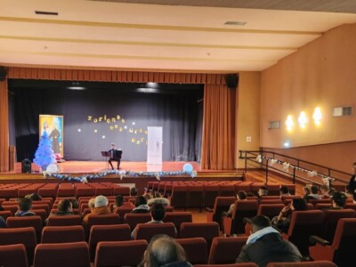 Un acordeonista, en el escenario de un salón de actos con público