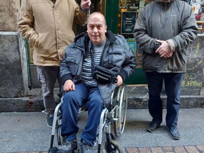 80ko hamarkadako punkean murgiltzen Hiru pertsona, horietako bat gurpil-aulkian, disko-denda baten aurrean