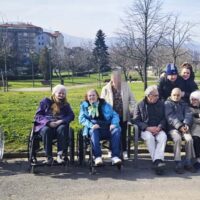 Un grupo de personas mayores sentadas en un banco y en sillas de ruedas