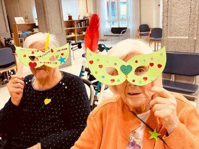Inauterietako maskaren familia tailerra Dos mujeres, con máscaras de carnaval hechas con cartulina