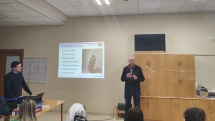 Dos hombres, dando una charla delante de un grupo d epersonas sentadas