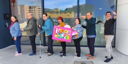 Varias personas en fila, mostrando un cartel con el texto