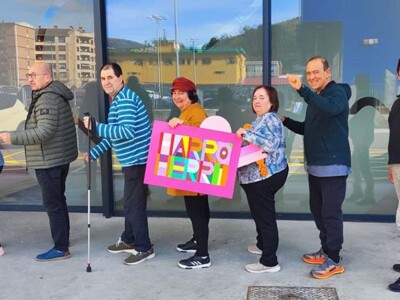 El Centro de Día de Daño Cerebral Aita Menni de Arrasate recibe el testigo de la Korrika Varias personas en fila, mostrando un cartel con el texto