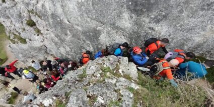 Al monte en silla de ruedas Un grupo de personas trasladan a otra en silla de ruedas por terreno de montaña