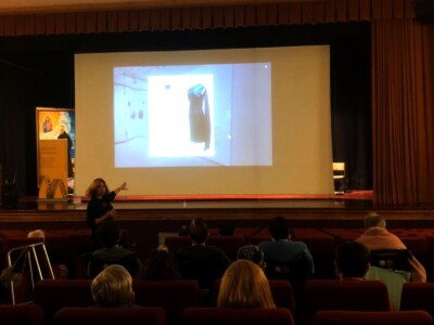 Un grupo amplio de personas en un salón de actos, mirando una pantalla