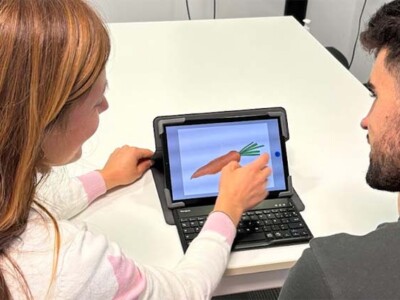 Una mujer y un hombre jóvenes, de espaldas, ante un pequeño ordenador portátil realizando un test