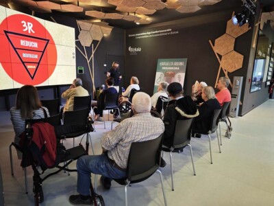Hondakinak murriztu, berrerabili, birziklatu eta tratatzeari buruz ikasten dugu Varias personas mayores, sentadas mirando una pantalla de una exposición