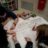 Dos chicas y un chico jóvenes, sentados en una mesa elaborando un cartel en el que puede leerse "Derechos de las personas con discapacidad intelectual"