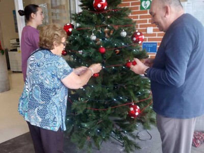 Una Navidad llena de actividades Una mujer y un hombre decoran un árbol de navidad