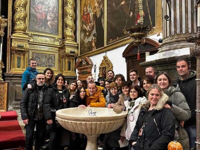 Un grupo de personas, en torno a una pila bautismal en una iglesia