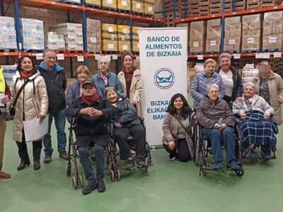 Visitamos el Banco de Alimentos de Bizkaia Varias personas, en un almacén, junto a un cartel del Banco de Alimentos de Bizkaia