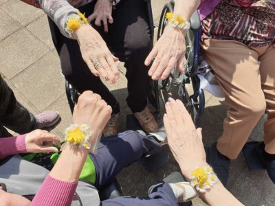 Paseos, flores y creatividad Varias mujeres mayores muestran sus manos, en las que hay pulseras hechas con margaritas