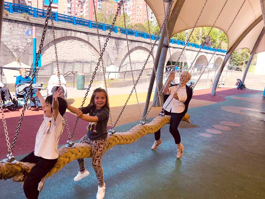 Volviendo a la niñez Un niño, una niña y iuna mujer mayor, en un balancín de un parque