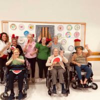 Un grupo de personas mayores, ante un panel con motivos andaluces
