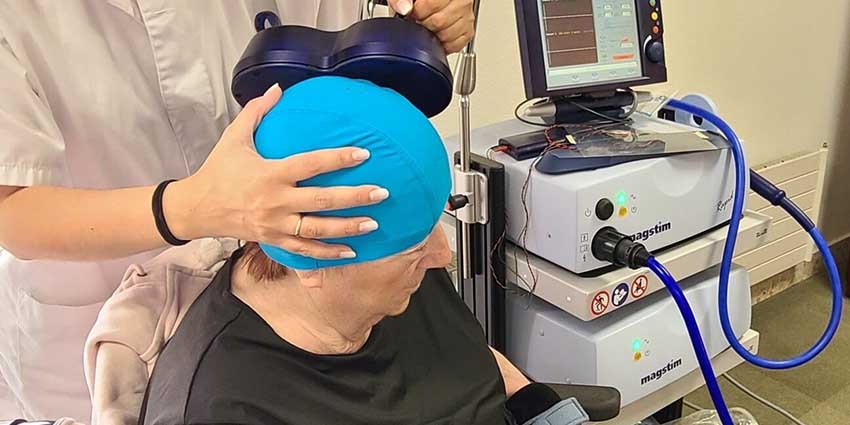 Incorporamos la neuromodulación cerebral mediante estimulación magnética transcraneal Una terapeuta aplica una estimulador magnético transcraneal sobre la cabeza de una mujer