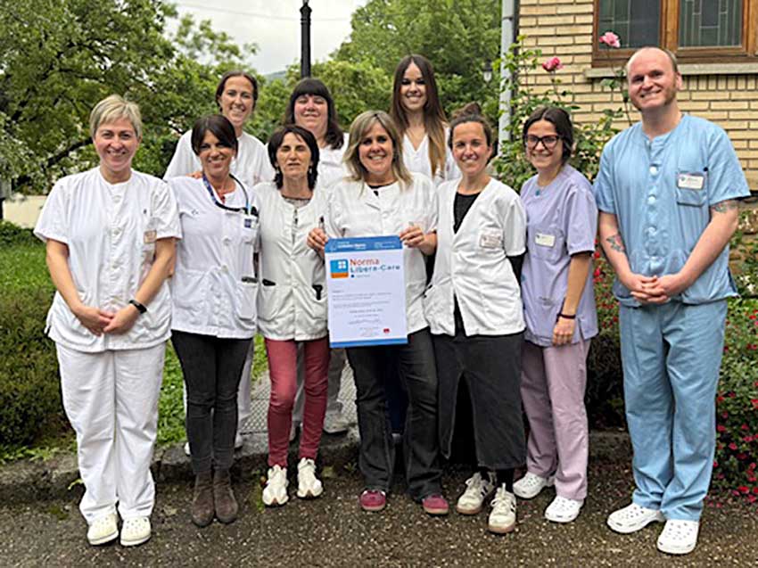 Gure adinekoen egoitza guztiek "Libera inicio" ziurtagiria osatu dute Varias personas, junto a una maqueta de una residencia de personas mayores, mostrando un certificado