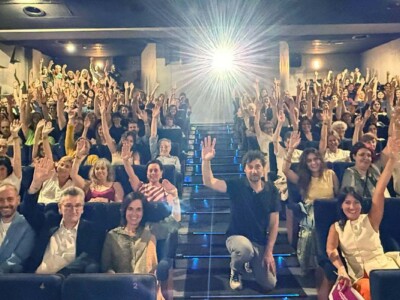 Ospitalarioak Fundazioa Euskadik "Votemos" filma aurkeztuko du Donostian Asistentes a una sala de cine levantan la mano como si votaran