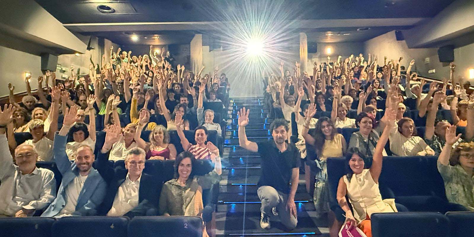 Fundación Hospitalarias presenta en San Sebastián la película "Votemos" Asistentes a una sala de cine levantan la mano como si votaran