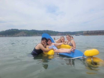 Tres mujeres con discapacidad intelectual, una de ellas en una silla acuática especial, se bañan junto a una monitora