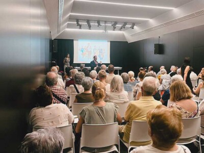 Ayudamos a hacer un Bilbao más amable para las personas mayores Un amplio grupo de personas, en una sala frente a una pantalla