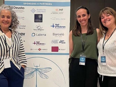 Tres mujeres posan ante el cartel del Congreso sobre el síndrome CTNNB1 en Bilbao