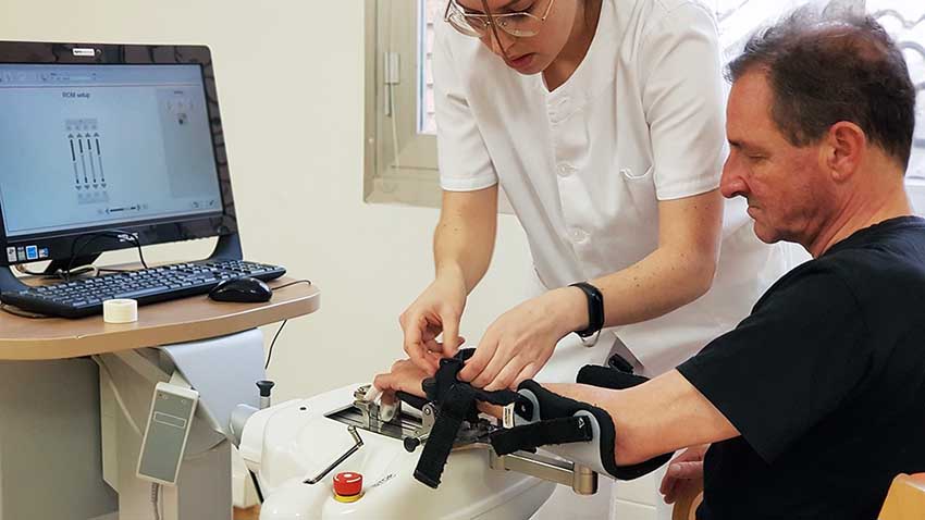 Pronóstico y expectativas en la rehabilitación del daño cerebral: hacia un modelo de acompañamiento honesto Una terapeuta ajusta el dispositivo Amadeo de rehabilitación del miembro superior