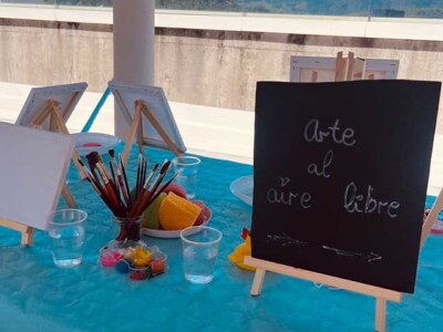 Pintura, juego, pulseras y helados Una mesa con una pizarra en la que se lee