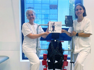 Dos fisioterapeutas, junto al exoesqueleto Atlas 2030, muestran un libro