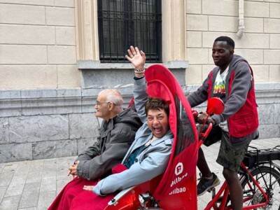 Recorriendo la ciudad en bicicleta Dos personas sentadas en la parte delantera de un triciclo de Cruz Roja