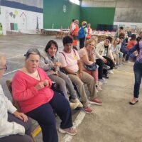 Varias mujeres con discapacidad intelectual, sentadas en sillas en un frontón