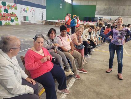 Usuarias del Centro Ibarra de Orozko participan en la fiesta anual de Rakataplá Varias mujeres con discapacidad intelectual, sentadas en sillas en un frontón