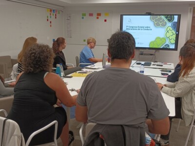 Varias personas, en una sala frente a una pantalla