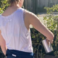 Una mujer, de espaldas, regando un huerto