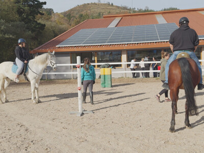 Emakume bat eta gizon bat zaldi gainean, zaldi-zentro bateko pistan