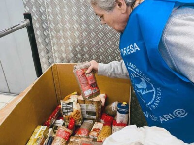 En la Gran Recogida del Banco de Alimentos de Bizkaia Una mujer mayor con un chaleco de voluntaria coloca alimentos en una caja