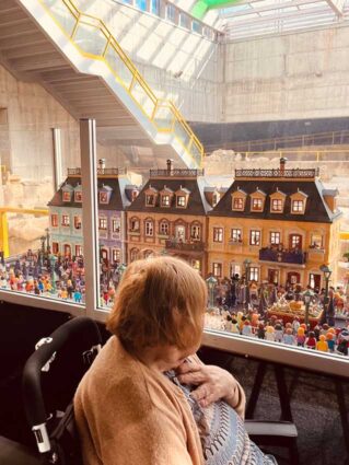 Una mujer mayor mira una maqueta