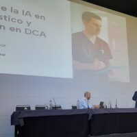 Un hombre habla desde un atril en presencia de otro sentado en una mesa