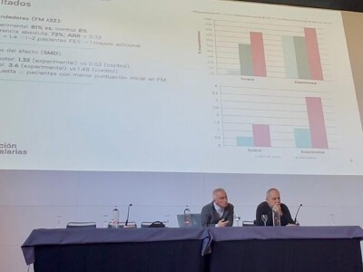 Presentamos los resultados de dos estudios en la Jornada de la Sociedad Española de Neurorrehabilitación Una mujer habla desde un atril en presencia de dos hombres sentados en una mesa