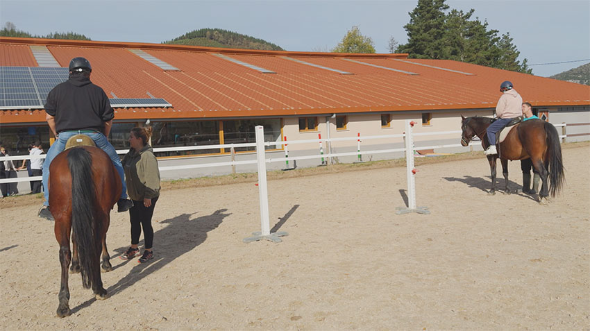Cuando tomar las riendas es más que guiar caballos Un hombre y una mujer montando a caballo en la pista de un centro hípico
