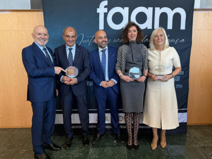 Hiru gizon eta bi emakume, batzuk sariak eskuetan, FAAMen logotipoa duen panel baten aurrean