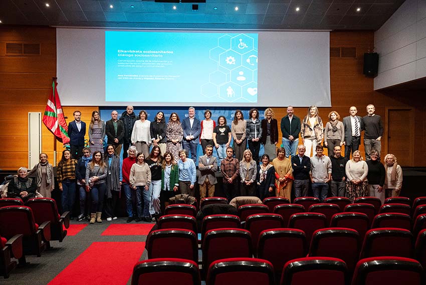 Un amplio grupo de personas posando en dos filas en un escenario