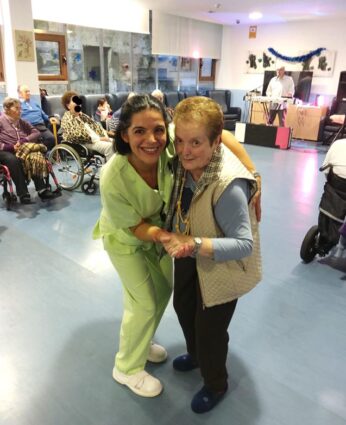 Una auxiliar de enfermería baila con una mujer mayor