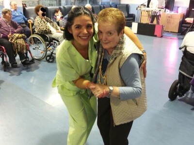 Una auxiliar de enfermería baila con una mujer mayor